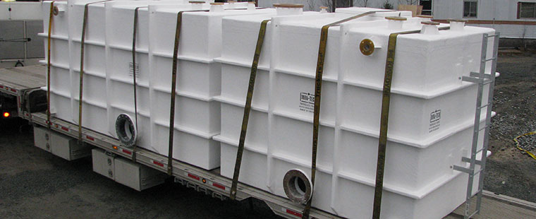 White fiberglass rectangular tanks secured on flatbed truck for delivery