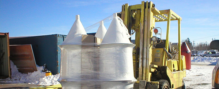 Forklift loading wrapped Dura-Tech fiberglass conical bottom tanks for delivery at snowy facility