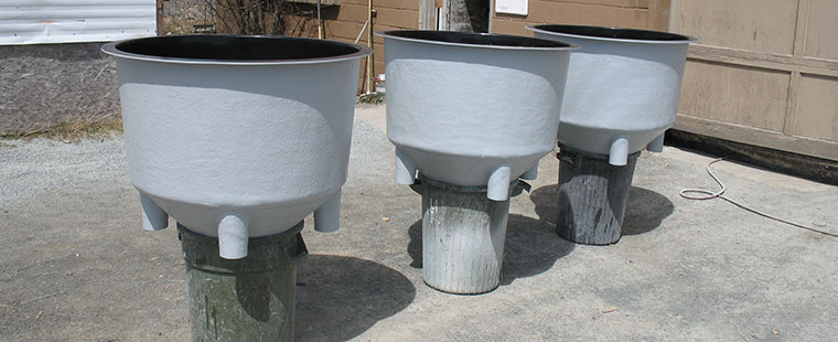 Dura-Tech fiberglass conical bottom tanks with center drain outlets displayed at manufacturing facility