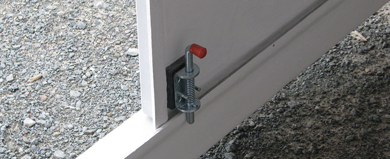 Dura-Tech fiberglass utility enclosure with red valve handle and metal clamp hardware installed on gravel surface
