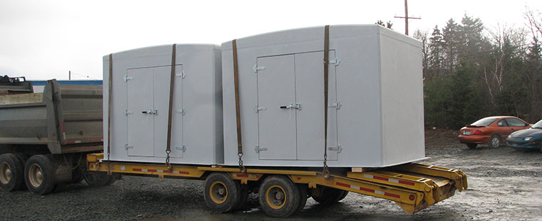 Large white Dura-Tech fiberglass utility enclosures being transported on flatbed truck trailer