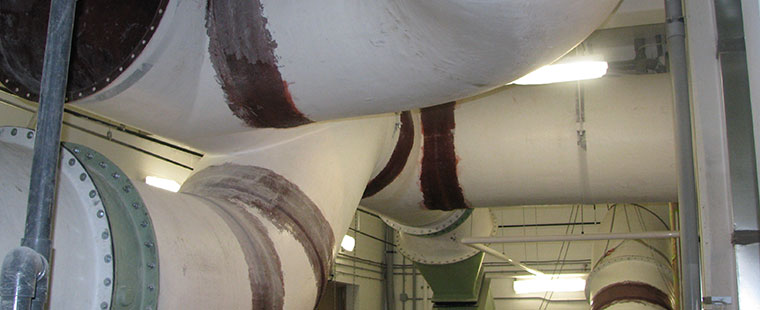 Large fiberglass ventilation ducts with flanged connections installed in industrial facility ceiling
