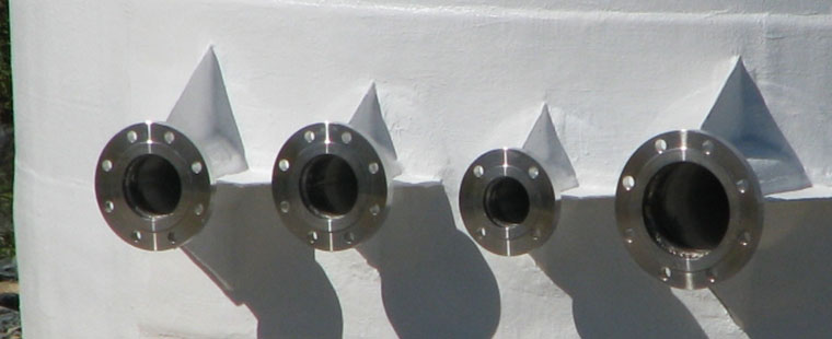 Four stainless steel flanged outlet connections on white Dura-Tech fiberglass vertical tank wall