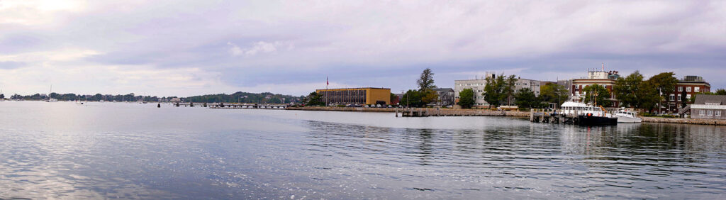 Coastal harbor with boats and waterfront buildings under cloudy sky